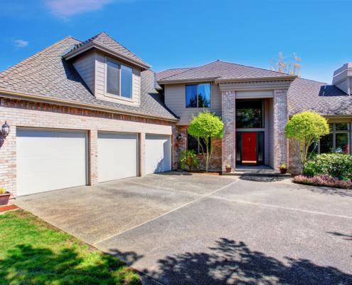 Large modern house with three garage spaces and concrete drivewa